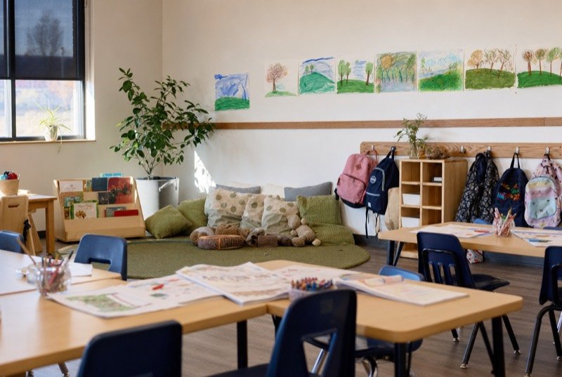 Workbooks on low tables and a cosy reading nook in a sunny room for children
