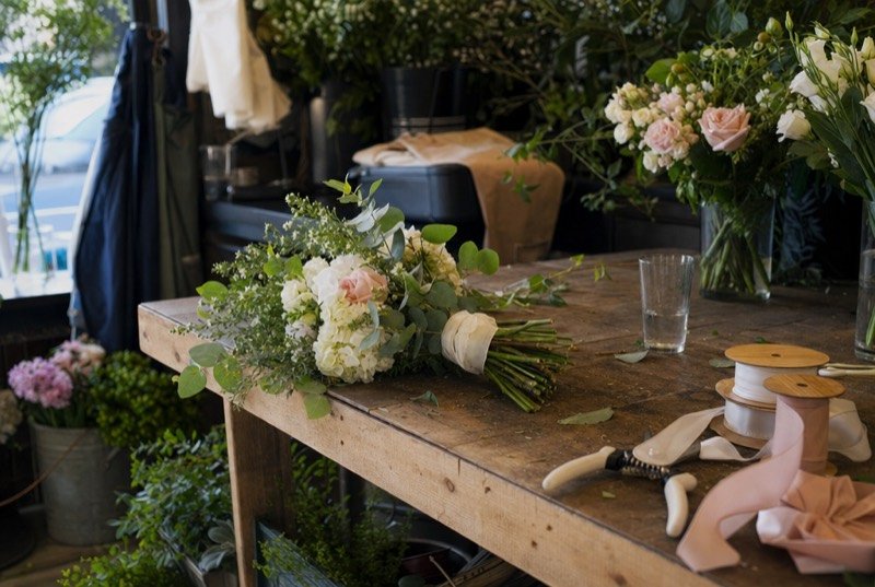 A florist’s workbench with a half-finished bridal bouquet, stems and ribbon, part of the wedding industry we plan SEO for