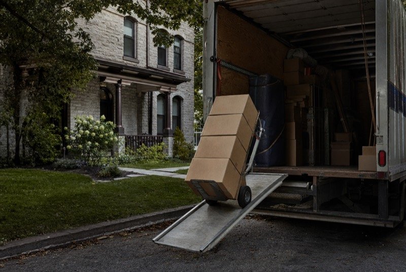 Boxes piled on a hand truck by a moving van’s ramp, an industry where SEO has to reach families before they arrive