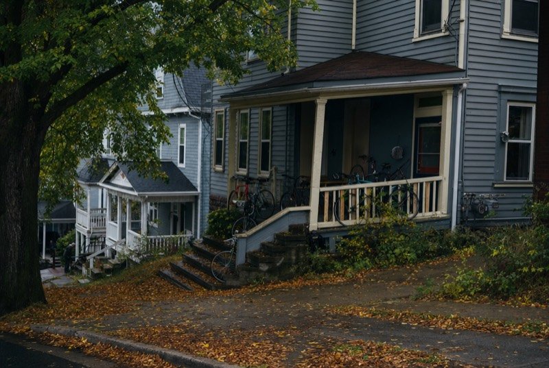 An older wood-frame multi-unit house with bicycles on the porch and leaves on the steps, typical of the rental industry our SEO serves